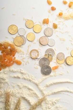 مجموعة من الأرز والزبيب والقمح والطحين والعملات المعدنية على خلفية بيضاء .