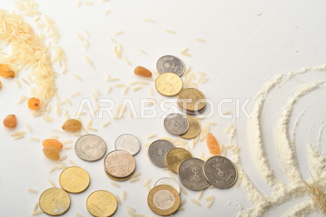 مجموعة من الأرز والزبيب والقمح والطحين والعملات المعدنية على خلفية بيضاء .