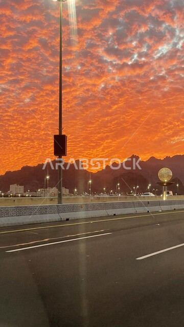 منظر السماء المليئة بالغيوم و المتلونة باللون البرتقالي أثناء الغروب في منطقة حائل في المملكة العربية السعودية، الشفق الأحمر في المناطق الطبيعية, لقطة لشكل السماء البديع وقت غروب الشمس فوق شوراع المدينة