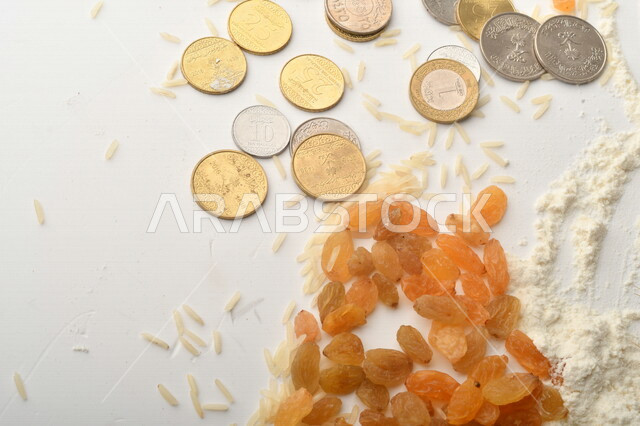 مجموعة من الأرز والزبيب والقمح والطحين والعملات المعدنية على خلفية بيضاء .