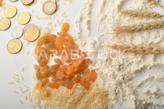 مجموعة من الأرز والزبيب والقمح والطحين والعملات المعدنية على خلفية بيضاء .