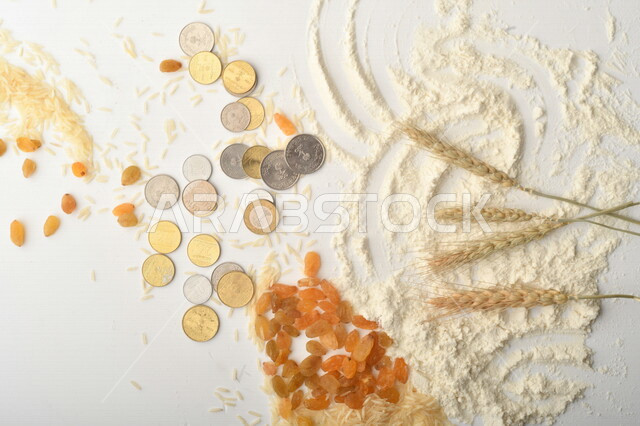 مجموعة من الأرز والزبيب والقمح والطحين والعملات المعدنية على خلفية بيضاء .