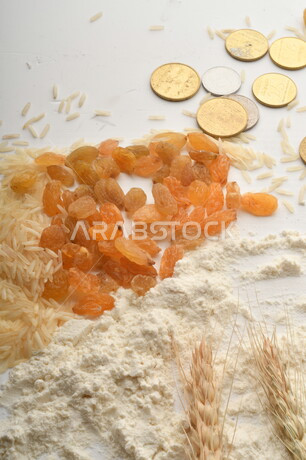 مجموعة من الأرز والزبيب والقمح والطحين والعملات المعدنية على خلفية بيضاء .