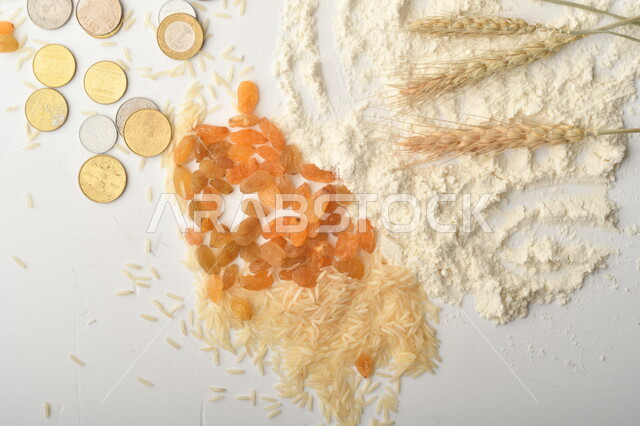 مجموعة من الأرز والزبيب والقمح والطحين والعملات المعدنية على خلفية بيضاء .