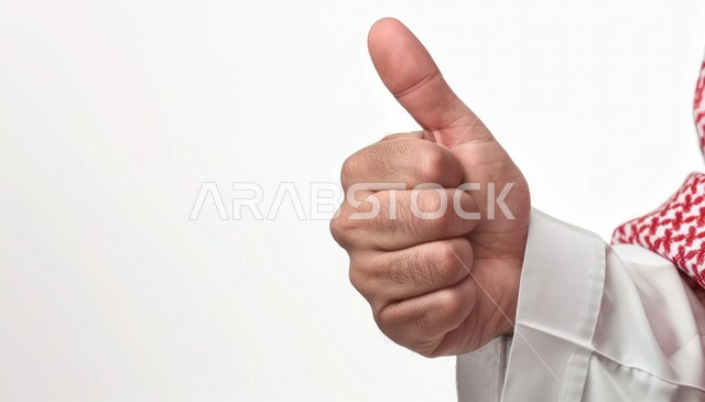 علامة الجودة والامتياز, بورتريه مقرب ليد رجل عربي خليجي سعودي يرتدي الثوب التقليدي والشماغ يرفع ابهامه بإيماءات الموافقة والقبول, الاعجاب والرضا لتحقيق أمر معين, مفهوم النجاح والفوز, خلفية بيضاء