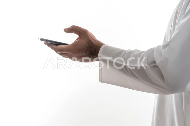 تصفح مواقع التواصل الإجتماعي، البحث عن عمل عن طريق الانترنت، بورتريه مقرب من الجانب لرجل عربي خليجي سعودي يرتدي الثوب التقليدي يحمل بيده الهاتف المحمول، متابعه آخر أخبار السوشال ميديا، خلفية بيضاء