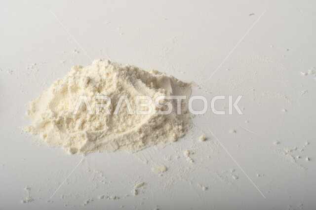 A handful of flour strewn on a white table.