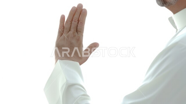 Hand gestures indicating command to not do something, silence and stop talking, close-up of hand of a Saudi Arabian Gulf man wearing traditional thobe raising his palm up in gesture of dislike, white background