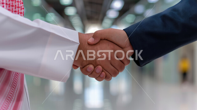 عقد صفقات عمل جديدة ناجحة بين رجال الأعمال، صداقات وتعارف وبناء علاقات اجتماعية، الشراكة في الأعمال والمشاريع، صورة مقربة ليدين رجلان سعوديان يقومان بمصافحة بعضهما، توسيع مجالات العمل
