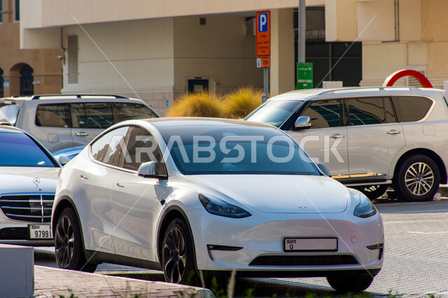  موديلات السيارات  الحديثة المتطورة، سيارة تسلا الكهربائية مركونة في الشارع أمام المسجد باللون الابيض في مدينة الشارقة بالإمارات العربية، الحد من انبعاث ثاني أكسيد الكربون، المحافظة على البيئة، استعمال الطاقة النظيفة