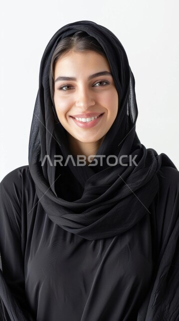 مفهوم الثقة بالنفس, تصاميم أزياء للمحجبات عصرية حديثة، الاهتمام بالمظهر الخارجي و الأناقة، بوتريه مقرب لامرأة عربية خليجية سعودية مبتسمة محجبة ترتدي عباءة سوداء تنظر إلى الكاميرا بإيماءات السعادة و السرور, خلفية بيضاء
