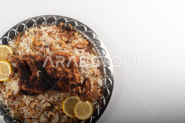 Popular rice dish with Madhbi chicken prepared in Saudi kitchen, brown rice with chicken decorated with noodles, traditional Saudi dish, ready-made traditional Saudi kitchen, white background
