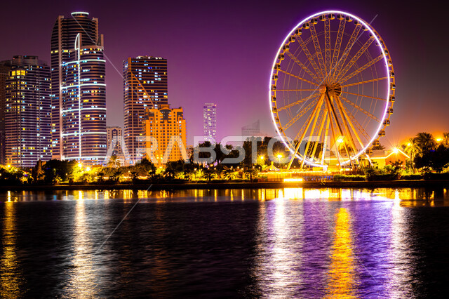 الفن الهندسي المعماري للأبراج وناطحات السحاب المضيئة ليلا المطلة على الخليج العربي، المعالم السياحية المشهورة، اماكن جذب واستقطاب السياح، اطلالة على الوجهة البحرية، كورنيش بحيرة خالد في مدينة الشارقة بالامارات العربية المتحدة