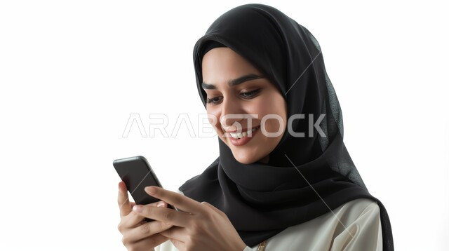 الدردشة مع الأهل والأصدقاء، إيماءات السعادة والسرور، استخدام الاجهزة التقنية الحديثة، بورتريه مقرب لامرأة عربية خليجية سعودية محجبة تحمل بيدها الهاتف المحمول تقوم بتصفح وسائل التواصل الاجتماعي، خلفية بيضاء