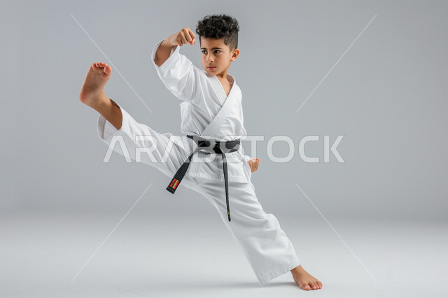 Kata movements application, portrait of a Saudi Arabian Gulf child practicing Japanese karate, white karate uniform with black belt, martial arts, training special fighting moves, full body image, gray background
