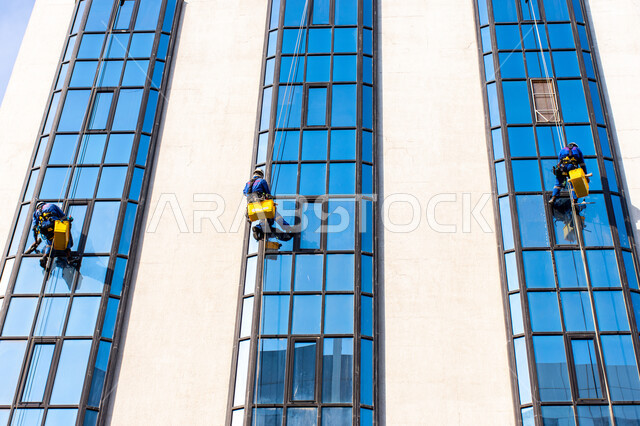 خدمة التنظيف في العمارات المرتفعة، الفن الهندسي المعماري للأبراج وناطحات السحاب، المنشآت الحديثة بديكورات وتصاميم متميزة في الإمارات العربية المتحدة، عمال عرب خليجيين إماراتيين يقومون بتنظيف الزجاج الخارجي لبناء مرتفع شاهق
