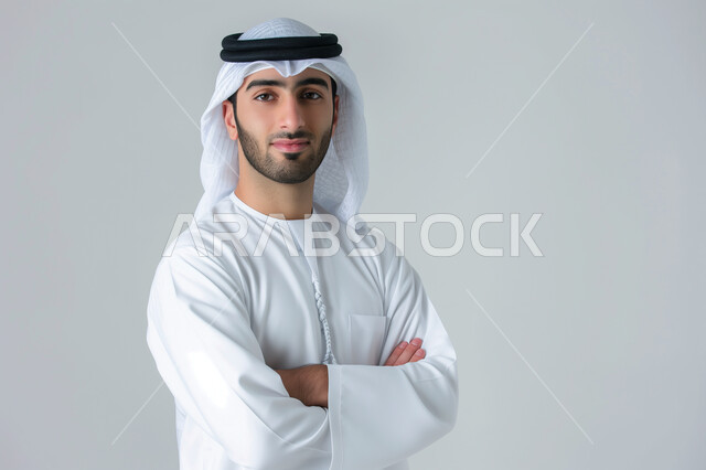 مفهوم الوسامة والرجولة، الاهتمام بالأناقة والمظهر الخارجي، التمعن والتركيز والتخطيط للمستقبل، بورتريه مقرب لرجل عربي خليجي سعودي يرتدي الثوب التقليدي ينظر الى الكاميرا بإيماءات الثقة بالنفس، التقاط صور شخصية للوثائق الرسمية, خلفية رمادية