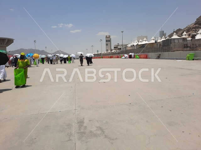 زيارة بيت الله الحرام, مجموعة من الحجاج والمعتمرين يحملون المظلات ويسيرون في منطقة رمي الجمرات في مكة المكرمة, أداء مناسك الحج والعمرة, أماكن إسلامية مقدسة