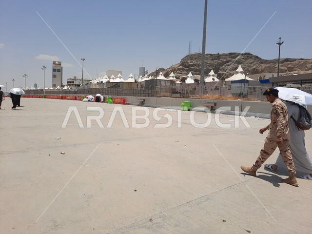 أماكن إسلامية مقدسة, زيارة بيت الله الحرام, مجموعة من الحجاج والمعتمرين يحملون المظلات ويسيرون في منطقة رمي الجمرات في مكة المكرمة, أداء مناسك الحج والعمرة