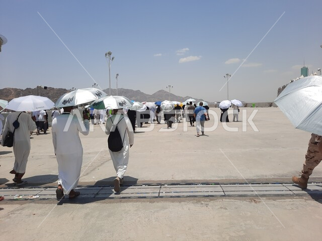 أداء مناسك الحج والعمرة, أماكن إسلامية مقدسة, زيارة بيت الله الحرام, مجموعة من الحجاج والمعتمرين يحملون المظلات ويسيرون في منطقة رمي الجمرات في مكة المكرمة
