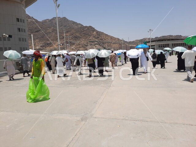 Islamic holy places, visiting the Holy House of Allah, a group of pilgrims and Umrah performers carrying umbrellas and walking in the Jamarat area in Mecca, performing Hajj and Umrah rituals