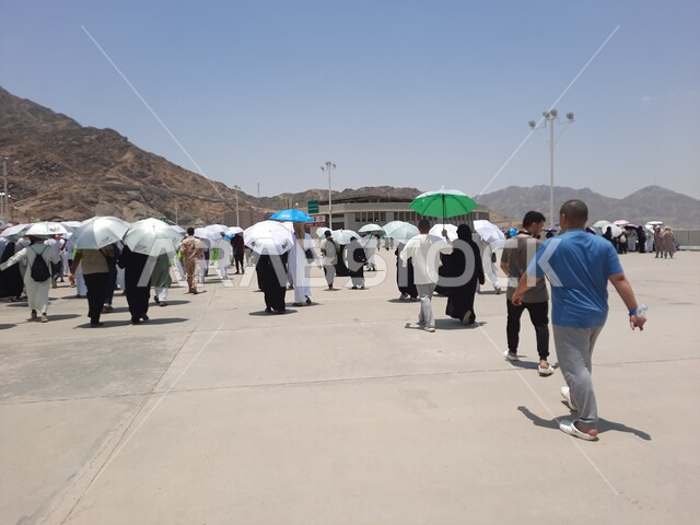 أداء مناسك الحج والعمرة, أماكن إسلامية مقدسة, زيارة بيت الله الحرام, مجموعة من الحجاج والمعتمرين يحملون المظلات ويسيرون في منطقة رمي الجمرات في مكة المكرمة