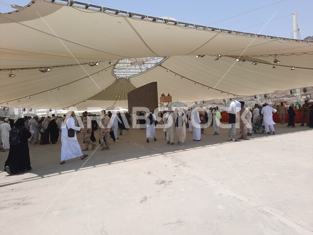 أداء مناسك الحج والعمرة، أماكن إسلامية مقدسة, مفهوم العبادة و التقرب من الله تعالى, مجموعة من الحجاج والمعتمرين يقفون تحت الشمسية في منطقة رمي الجمرات في مكة المكرمة