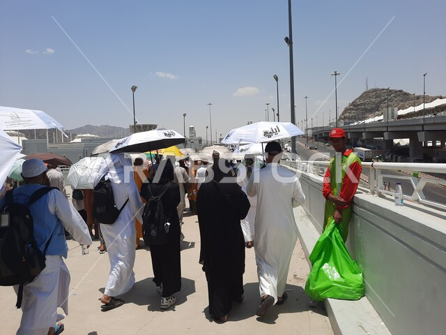 العبادة و التقرب إلى الله تعالى, زوار بيت الله الحرام يسيرون في منطقة جسر الجمرات في مكة المكرمة و يحملون المظلات, الحجاج المسلمين يقومون بأداء مناسك الحج والعمرة, أماكن إسلامية دينية مقدسة في المملكة العربية السعودية