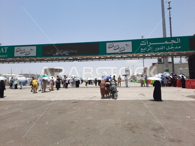 زوار بيت الله الحرام يسيرون في منطقة جسر الجمرات في مكة المكرمة و يحملون المظلات, الحجاج المسلمين يقومون بأداء مناسك الحج والعمرة, أماكن إسلامية دينية مقدسة في المملكة العربية السعودية, العبادة و التقرب إلى الله تعالى