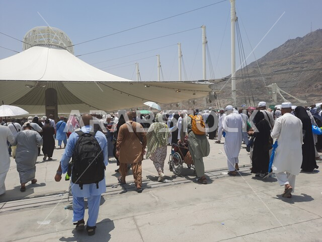 مفهوم العبادة و التقرب من الله تعالى, مجموعة من الحجاج والمعتمرين يسيرون تحت المظلات في منطقة رمي الجمرات في مكة المكرمة, زوار بيت الله الحرام يقومون بأداء مناسك الحج والعمرة, أماكن إسلامية دينية مقدسة