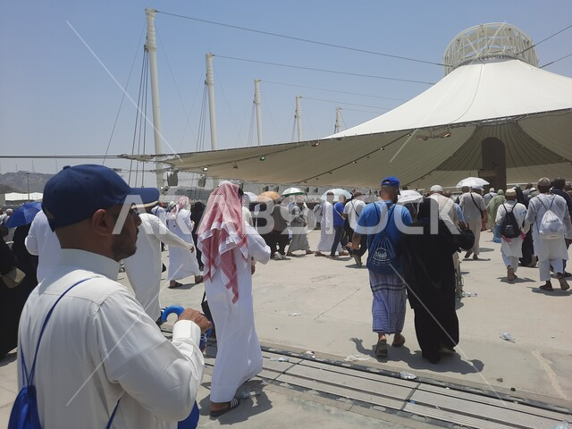 زوار بيت الله الحرام يقومون بأداء مناسك الحج والعمرة، أماكن إسلامية دينية مقدسة, مفهوم العبادة و التقرب من الله تعالى, مجموعة من الحجاج والمعتمرين يسيرون تحت المظلات في منطقة رمي الجمرات في مكة المكرمة