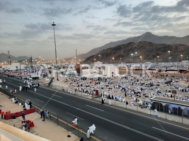 Worshiping and getting closer to God in sacred Islamic religious landmarks and places, pilgrims of the Sacred House of God in Muzdalifah wearing the Ihram dress in Mecca in the Kingdom of Saudi Arabia, performing the rituals of Hajj and Umrah.