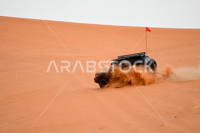 Driving a four-wheel drive vehicle (dune bashing) in the middle of the desert, safari adventures on the sand dunes, fun desert activities, an exciting adventure on the soft golden sands in the deserts of the Kingdom of Saudi Arabia, enjoying practicing hobbies