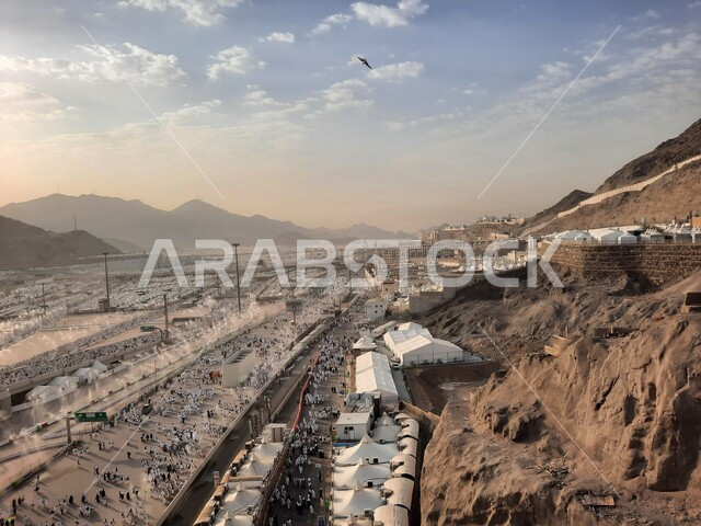 مجموعة من الحجاج يسيرون على جسر الجمرات بمكة المكرمة، أداء مناسك الحج والعمرة, أماكن و معالم دينية إسلامية مقدسة في المملكة العربية السعودية, زيارة بيت الله الحرام في وقت النهار