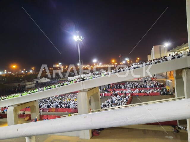 مجموعة من الحجاج يسيرون على جسر الجمرات بمكة المكرمة، أداء مناسك الحج والعمرة, أماكن و معالم دينية إسلامية مقدسة في المملكة العربية السعودية, زيارة بيت الله الحرام في وقت الليل