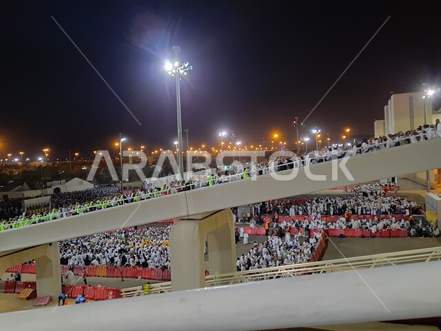 A group of pilgrims walk on the Jamarat Bridge in Mecca, performing Hajj and Umrah rituals, sacred Islamic religious places and landmarks in the Kingdom of Saudi Arabia, visiting the Holy House of God at night