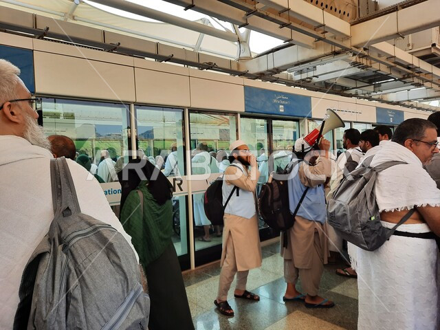 A picture of pilgrims wearing white ihram clothes, moving on the Haramain Express Train in Makkah Al-Mukarramah, Al-Russeifa Station in Makkah Al-Mukarramah, Hajj transportation services to the Grand Mosque, safe and comfortable transportation services during the Hajj season