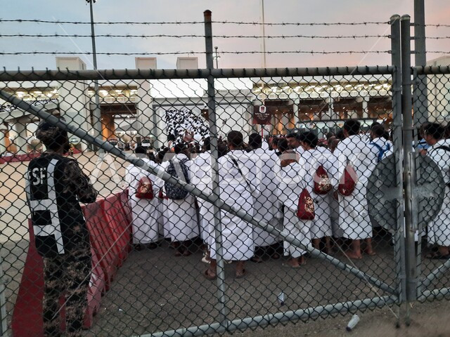 A picture of pilgrims wearing white ihram clothes standing waiting for the Haramain Express Train in Makkah Al-Mukarramah, Al-Russeifa Station in Makkah Al-Mukarramah, Hajj transportation services to the Grand Mosque, safe and comfortable transportation services during the Hajj season