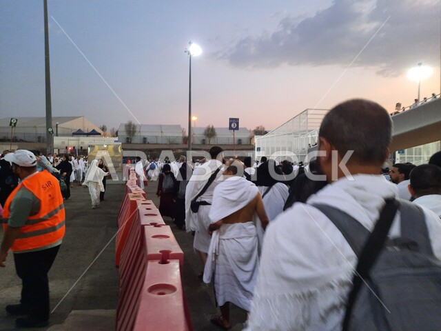 A picture of pilgrims wearing white ihram clothes standing waiting for the Haramain Express Train in Makkah Al-Mukarramah, Al-Russeifa Station in Makkah Al-Mukarramah, Hajj transportation services to the Grand Mosque, safe and comfortable transportation services during the Hajj season