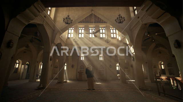 الاجتهاد في العباده والطاعة في شهر رمضان المبارك، مفهوم الدعاء والتضرع والترجي، رجل عربي خليجي سعودي يقف داخل المسجد، التوبة والرجوع الى الله، دخول أشعة الشمس الى الأماكن الاسلامية