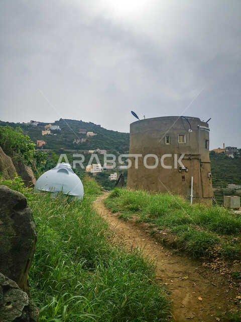  الأشجار والنباتات الخضراء على السفوح , ممر طويل بين الجبال في وقت النهار,الاستمتاع بالمناظر الطبيعية في الأماكن السياحية في المملكة العربية السعودية،البيوت السكنية فوق القمم والمرتفعات الجبلية في محافظة فيفاء في مدينة جازان،خلفية السماء المليئة بالغيوم البيضاء