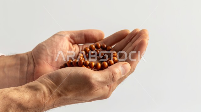 The concept of worship and drawing closer to God Almighty, performing religious duties and acts of obedience, a close-up portrait of the hand of a Saudi Arabian Gulf man holding a wooden prayer rosary with expressions of supplication, gray background