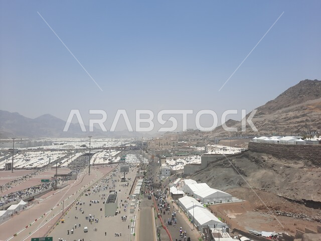 زوار بيت الله الحرام يسيرون في منطقة جسر الجمرات في مكة المكرمة و يحملون المظلات, أماكن إسلامية دينية مقدسة في المملكة العربية السعودية, العبادة و التقرب إلى الله تعالى, الحجاج المسلمين يقومون بأداء مناسك الحج والعمرة