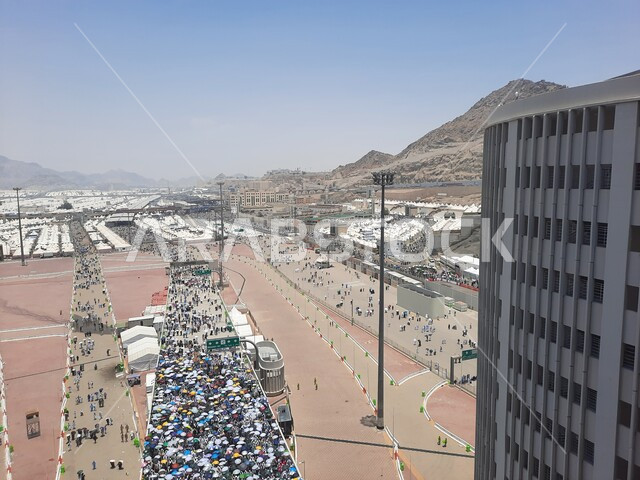 زوار بيت الله الحرام يسيرون في منطقة جسر الجمرات في مكة المكرمة و يحملون المظلات, أماكن إسلامية دينية مقدسة في المملكة العربية السعودية, العبادة و التقرب إلى الله تعالى, الحجاج المسلمين يقومون بأداء مناسك الحج والعمرة