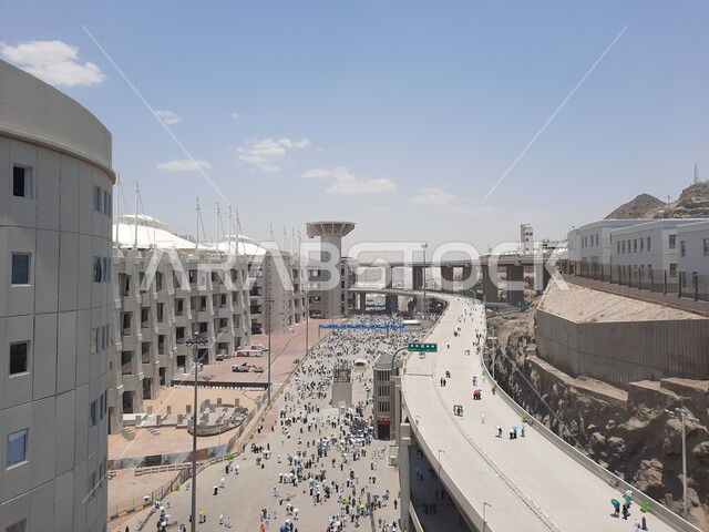 منظر جماعي لمجموعة من الحجاج يسيرون على جسر الجمرات بمكة المكرمة، مفهوم العبادة والتقرب إلى الله، أداء مناسك الحج والعمرة, أماكن و معالم دينية إسلامية مقدسة في المملكة العربية السعودية, زيارة بيت الله الحرام
