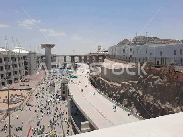 Group view of a group of pilgrims walking on the Jamarat Bridge in Mecca, the concept of worship and drawing closer to God, performing the Hajj and Umrah rituals, sacred Islamic religious places and landmarks in the Kingdom of Saudi Arabia, visiting the Holy House of God
