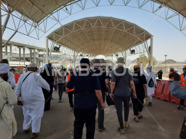 خدمات نقل آمنة و مريحة في موسم الحج، صورة مقربة لحجاج بيت الله الحرام بملابس الإحرام البيضاء يقفون ينتظرون قطار الحرمين السريع في مكة المكرمة بعد رمي الجمرات ، محطة الرصيفة في مكة المكرمة ، وسائل نقل الحجاج للمسجد الحرام