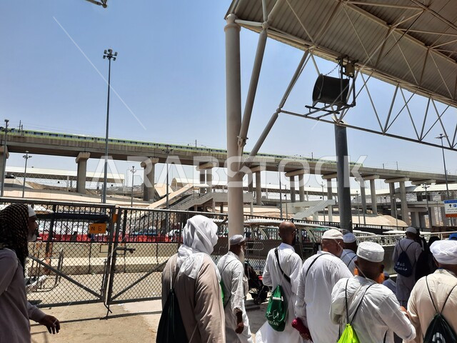 خدمات نقل آمنة و مريحة في موسم الحج، صورة مقربة لحجاج بيت الله الحرام بملابس الإحرام البيضاء يقفون ينتظرون قطار الحرمين السريع في مكة المكرمة بعد رمي الجمرات ، محطة الرصيفة في مكة المكرمة ، وسائل نقل الحجاج للمسجد الحرام