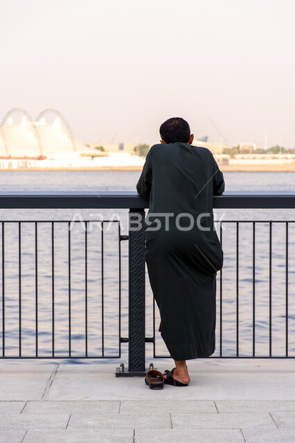 توافد الزوار والأشخاص للاستمتاع بالمناظر الطبيعية على الكورنيش،  معالم ومناطق وواجهات سياحية مشهورة في إمارة دبي، البيوت والمباني السكنية بالقرب من الشاطئ، لقطة من الخلف لرجل عربي يقابل البحر في منطقة الخور بمدينة دبي بالإمارات العربية