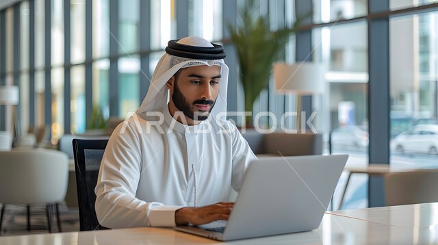 Using modern devices to accomplish tasks, a Saudi Arabian Gulf man wearing traditional thobe and shemagh sitting in the office working on his laptop, integrating advanced technologies into daily life